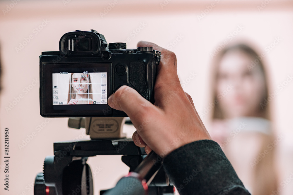 Selective focus of videographer working with attractive model in photo studio Selective focus of videographer working with attractive model in photo studio