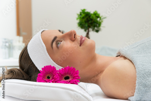 Zrelaksowana kobieta leży w salonie spa. Relaks w spa. Salon urody. Medycyna estetyczna, piękna twarz kobiety. 
