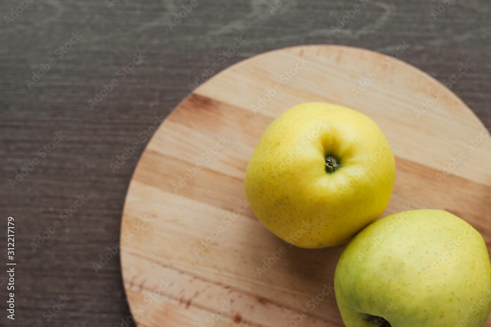 Ripe green apples on a round wooden cutting board on the table copy space. Harvest apples. Ripe green apples on a round wooden cutting board on the table copy space. Harvest apples.
