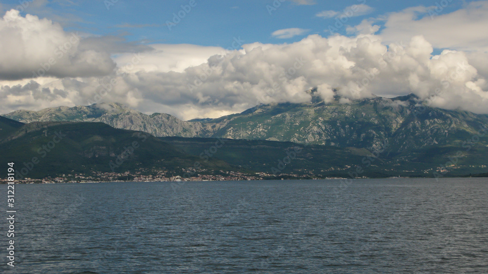 panoramic view from the ship to Kotor bay and the surrounding mountains, blue sky with white clouds, Montenegro
