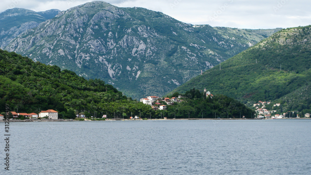 panoramic view from the ship to Kotor bay and the surrounding mountains, blue sky with white clouds, Montenegro