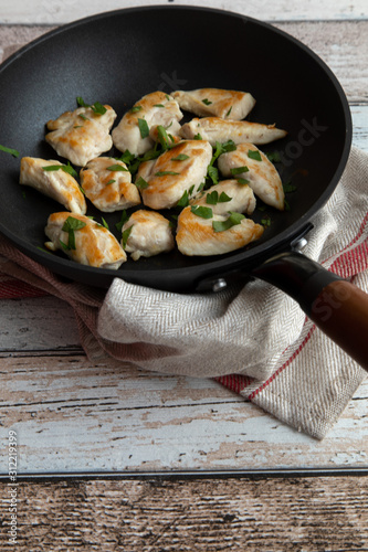 Roasted chicken breast with cut parsley in antique looking frying pan