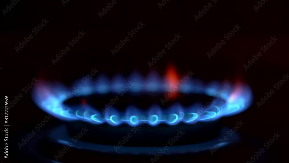 Natural gas kindling in dark kitchen. Blue flames of fire burning on gas stove. Slow motion shot