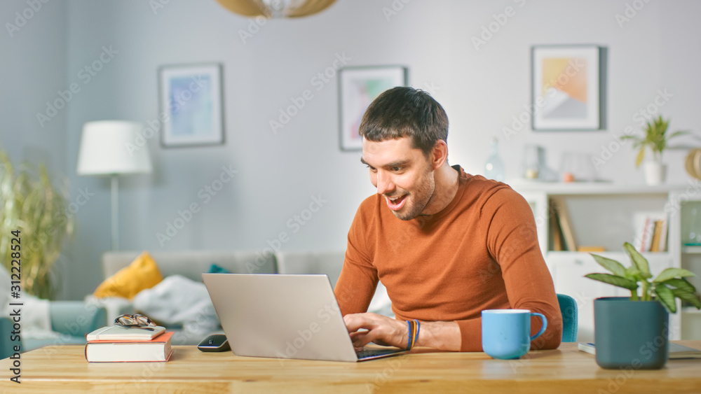 Portrait of Excited Successful Smiling Man Working on Laptop at Home, Receives Good News. Man Working From Home Office.
