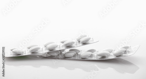 White tablets in blister package on white background. Global healthcare concept. Antibiotics drug resistance. Antimicrobial capsule pills. Pharmaceutical industry. Pharmacy.
