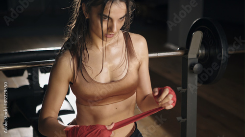 Beautiful and fit female fighter getting prepared for the fight or training.