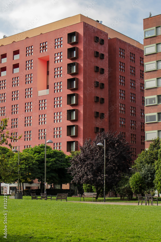 Façade rouge d'un immeuble moderne avec un parc
