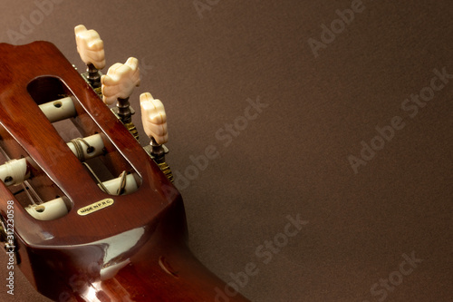 Fotografija Acoustic Guitar, partial close-up view of headstock and capstan or string post, dusty abandoned on brown background