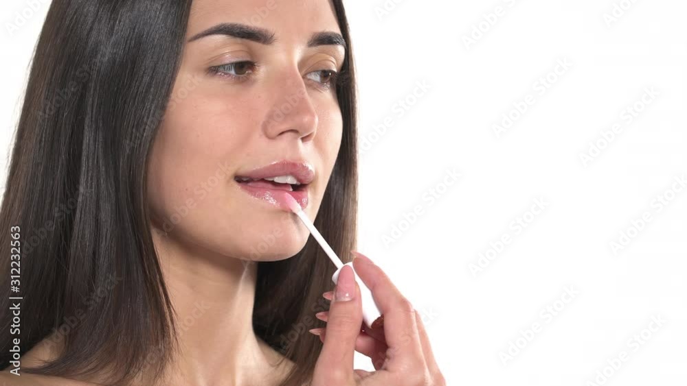 Woman applying pink lip gloss. Lips makeup, cosmetic product usage Woman applying pink lip gloss. Lips makeup, cosmetic product usage