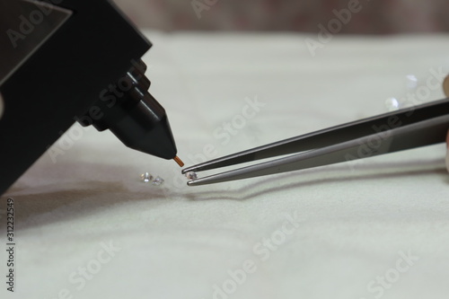 Human Hand holding Diamonds selector machine checking for real Diamond