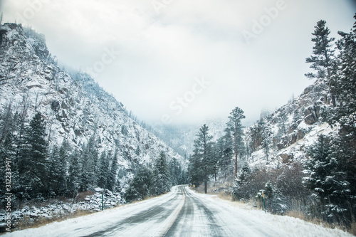 highway through the mountains of colorado with snow and pine trees