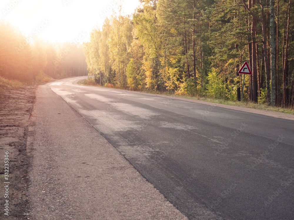 Fototapeta premium Empty asphalt road in a forest. New surface without marking, Warm sunny day, Nobody. Sun flare.