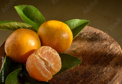 Fresh tangerines with leaves on wooden background.