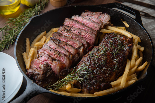 sirloin steak with french fries in iron skillet pan photo