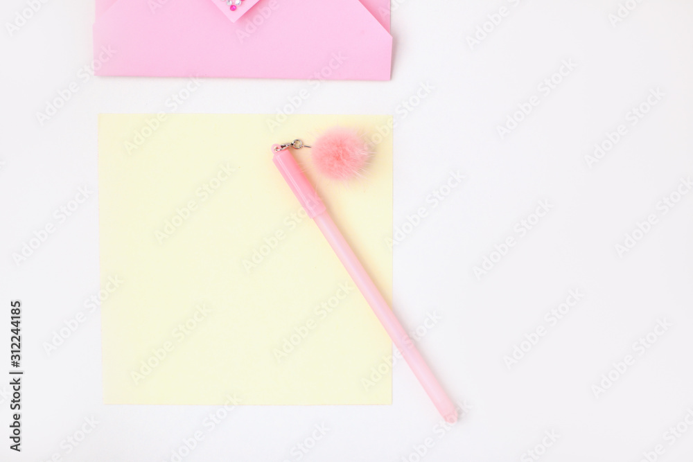 Flat lay: yellow paper, pink envelope with rhinestones, pen with pompom. Making postcard in envelope for Valentine's Day. Do it yourself. Photo from the series
