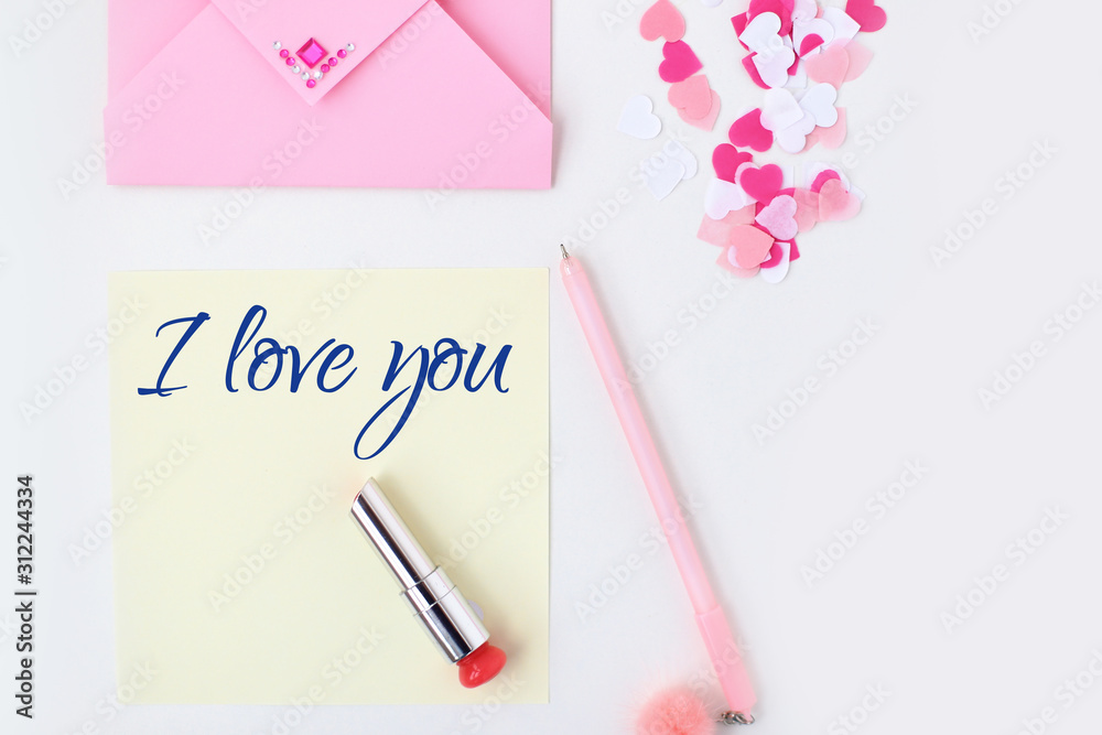 Flat lay: yellow paper, pink envelope, pen, pompom, perfume, lipstick, confetti hearts, lip print, i love you text. Making postcard in envelope for Valentine's Day.Do it yourself.Photo from the series Flat lay: yellow paper, pink envelope, pen, pompom, perfume, lipstick, confetti hearts, lip print, i love you text. Making postcard in envelope for Valentine's Day.Do it yourself.Photo from the series