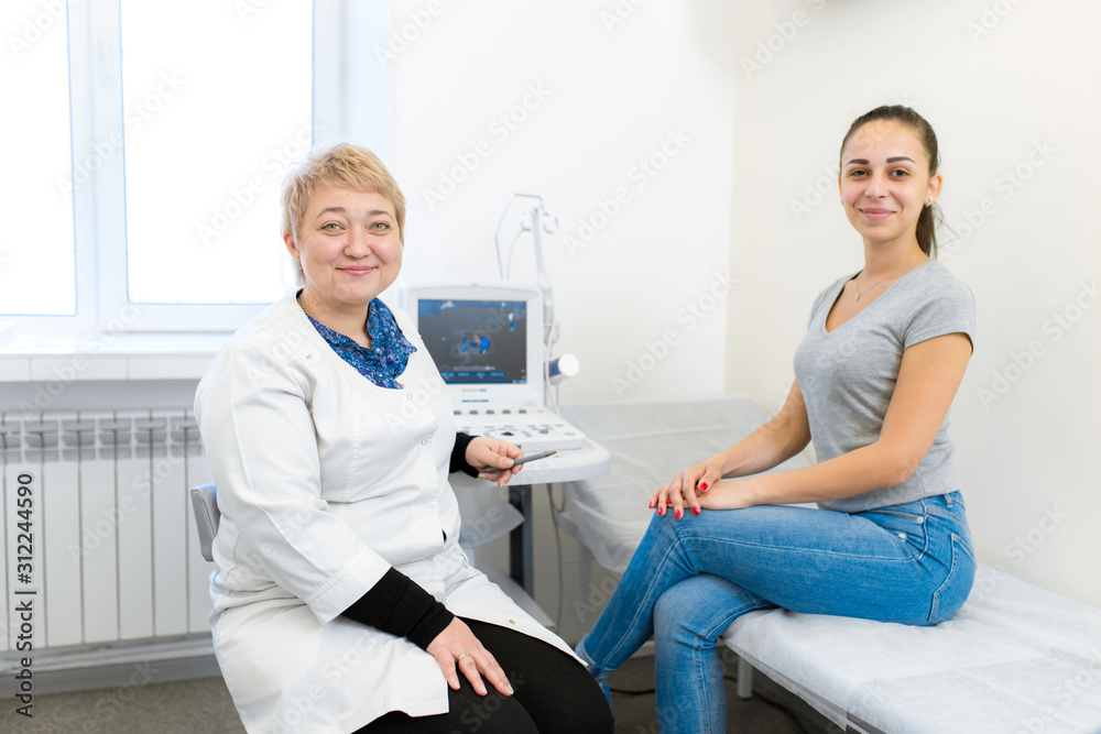 Obraz premium a doctor with a smile on his face consults a girl patient after an ultrasound diagnosis. Professional Medical Examination.