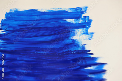 Smears of dark blue paint on a white sheet of paper. Close-up. View from above.