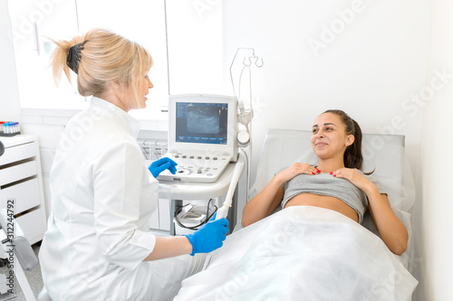 A gynecologist sets up an ultrasound machine to diagnose a patient who is lying on a couch. A transvaginal ultrasound scanner of the internal organs of the pelvis. Female health concept