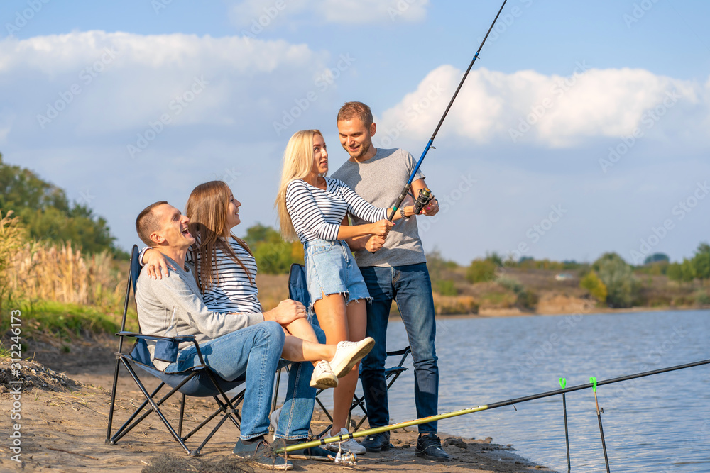 Group of young friends fishing on the pier by lakeside Group of young friends fishing on the pier by lakeside