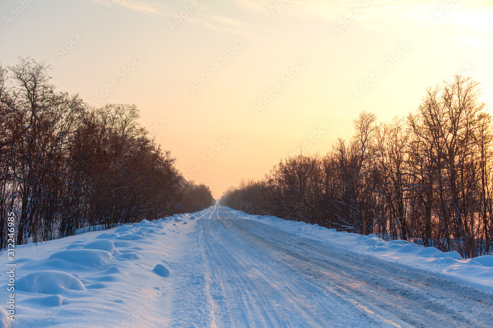 Winter poorly cleared road. Road in the countryside strewn with snow. Winter landscape with snowdrifts