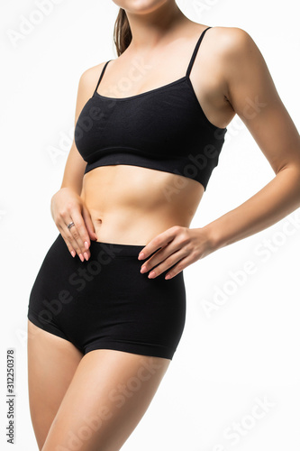 Young beautiful woman body on gray background in black sport clothes