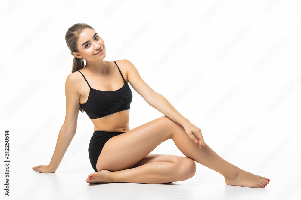 Young beautiful woman with perfect body in black underwear sitting on floor isolated on white background