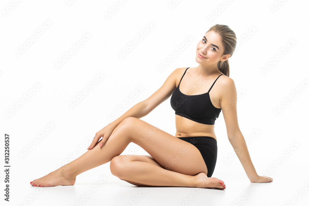 Young beautiful woman with perfect body in black underwear sitting on floor isolated on white background