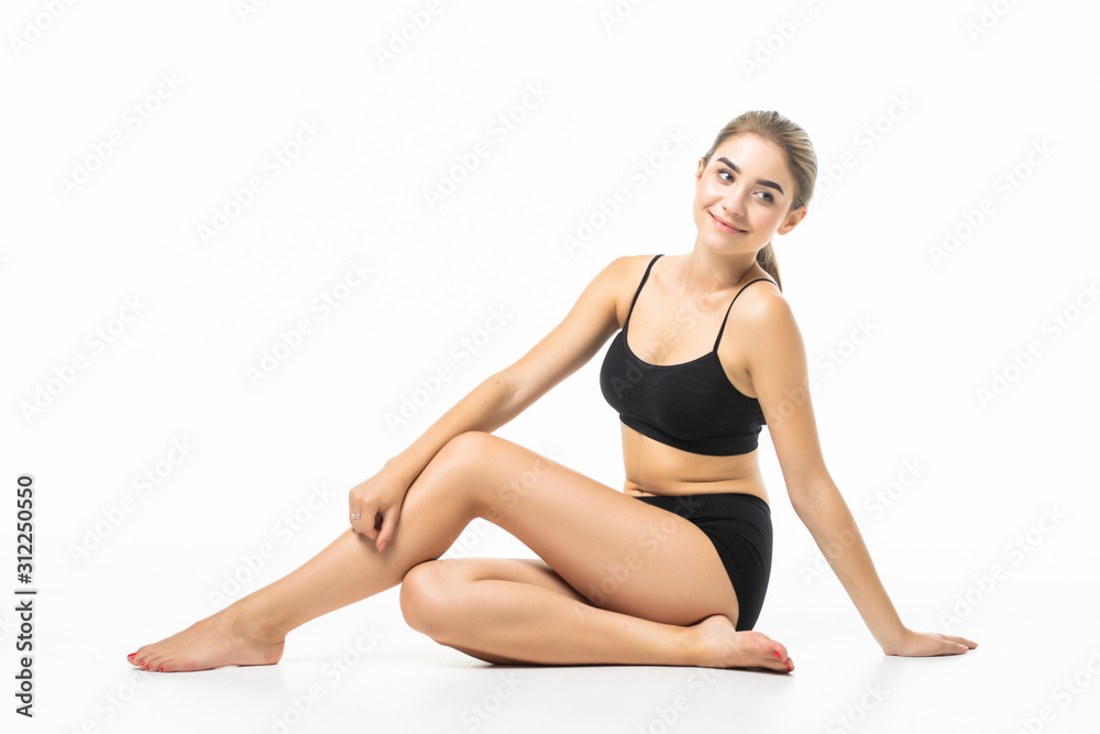 Young beautiful woman with perfect body in black underwear sitting on floor isolated on white background