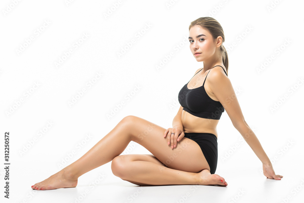 Feeling satisfied. Girl with perfect slim toned young body sitting in the studio with white background.