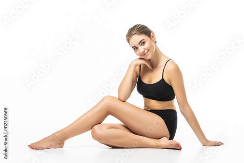 Feeling satisfied. Girl with perfect slim toned young body sitting in the studio with white background.