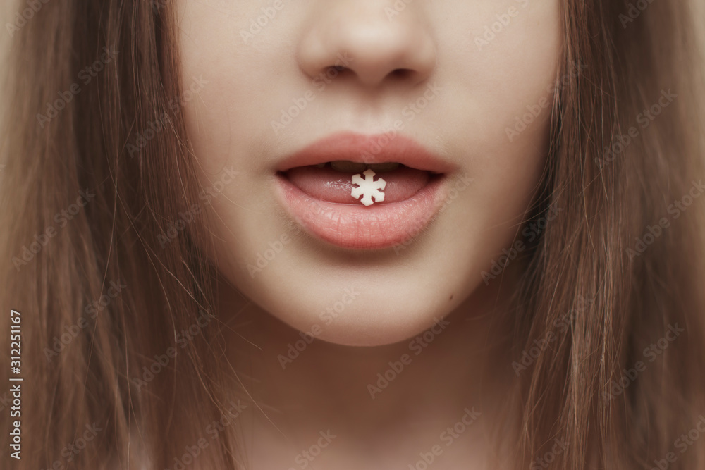 A little white snowflake on the girl’s tongue. Sweet candy in New Year's form.