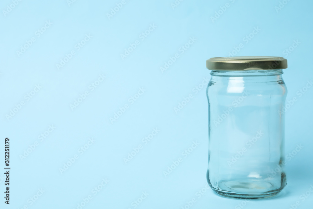 Closed empty glass jar on light blue background, space for text Closed empty glass jar on light blue background, space for text