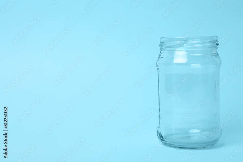 Open empty glass jar on light blue background, space for text Open empty glass jar on light blue background, space for text