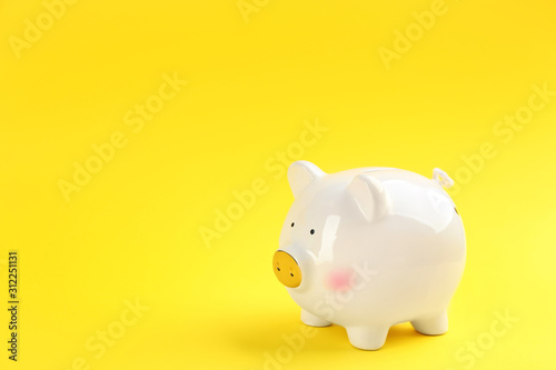 White piggy bank on yellow background. Space for text