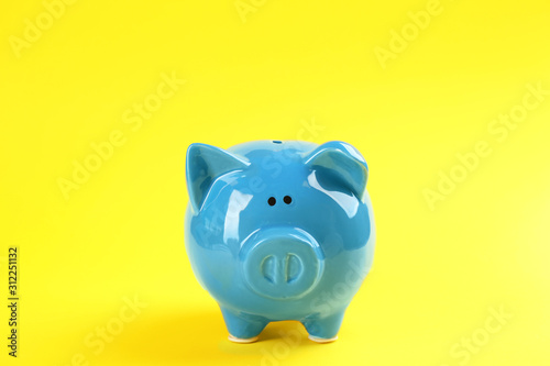 Cute blue piggy bank on yellow background