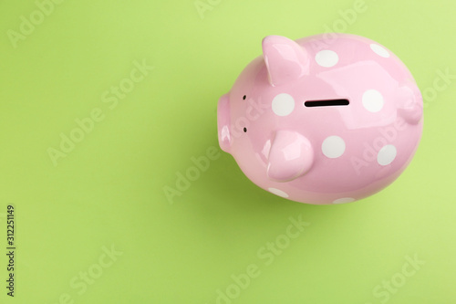 Pink piggy bank on green background, top view. Space for text