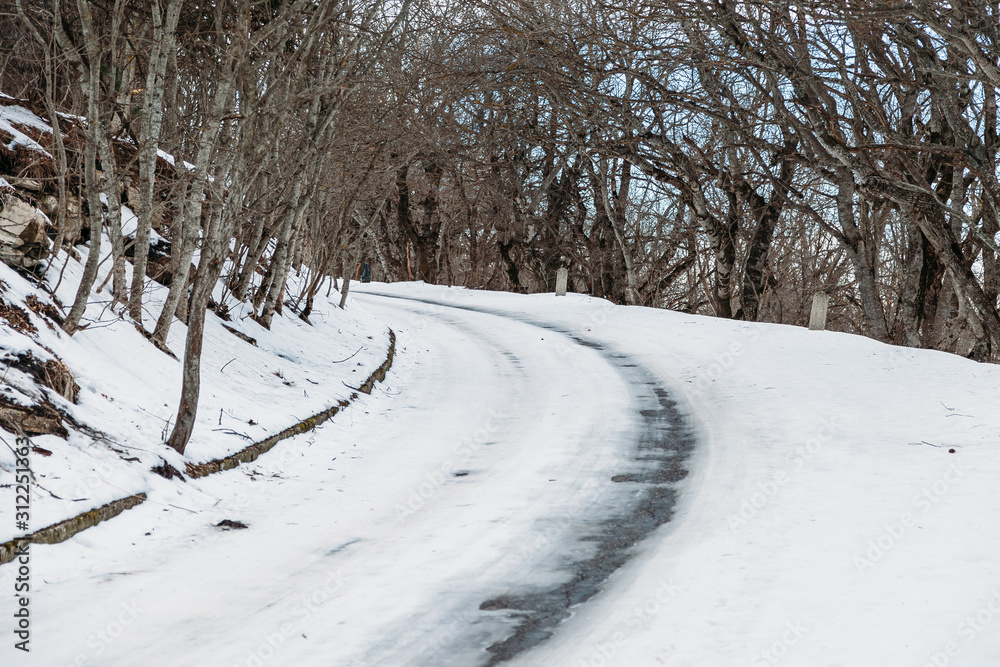 Naklejka premium dangerous turn of snow-covered road in the forest