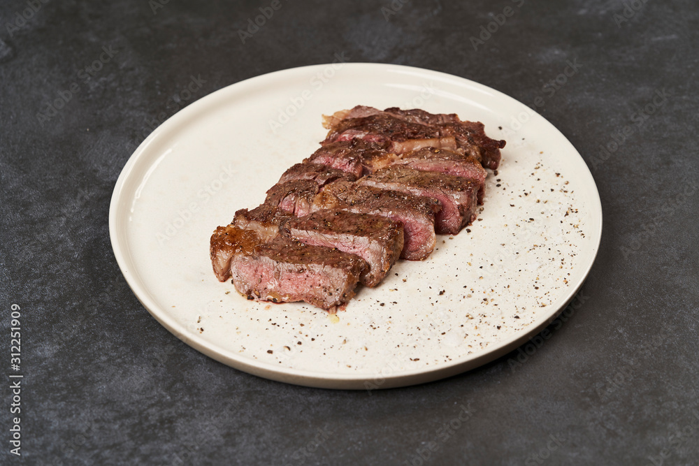 Grilled beef steak with spices on a white tray, close-up