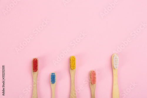 Toothbrushes made of bamboo on pink background, flat lay. Space for text