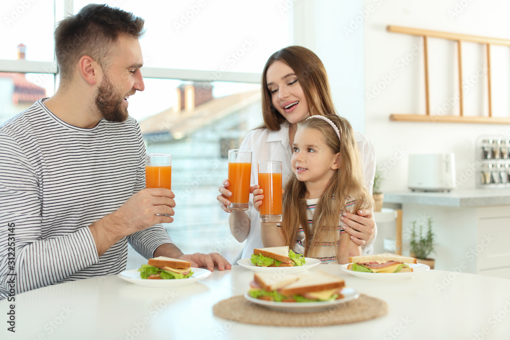 Happy family having breakfast with sandwiches at table in kitchen Happy family having breakfast with sandwiches at table in kitchen