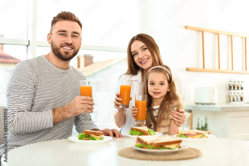 Happy family having breakfast with sandwiches at table in kitchen