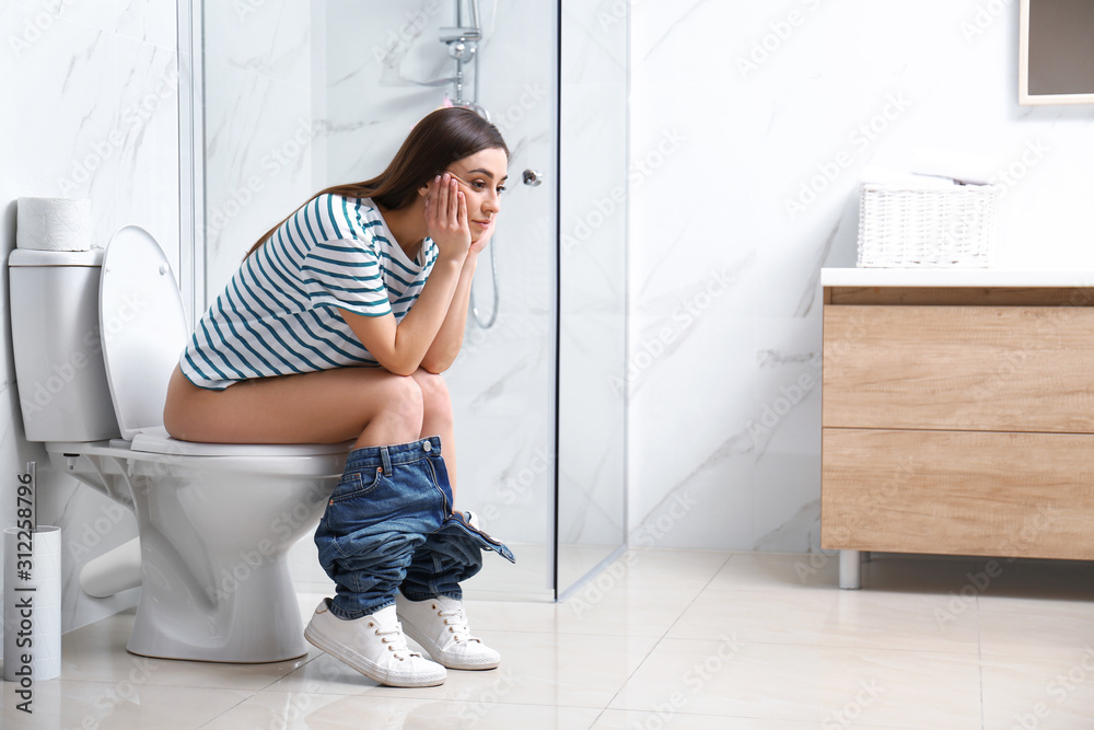 A beautiful girl is sitting on the toilet. Woman in panties relaxing on the  toilet with the phone. Pensive teenage girl sits with panties on the  toilet. 11025526 Stock Photo at Vecteezy