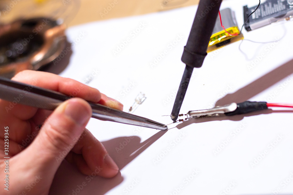Worker in a workshop soldering an electric diode Worker in a workshop soldering an electric diode