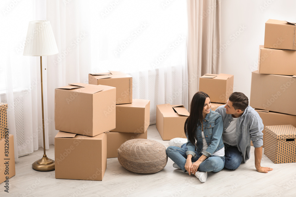 Happy couple in room with cardboard boxes on moving day Happy couple in room with cardboard boxes on moving day