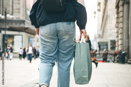 A woman or a female with a bag after shopping walks down the street