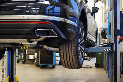 Modern luxury car SUV on a lift in a service center. The concept of service and repair of a modern luxury car.