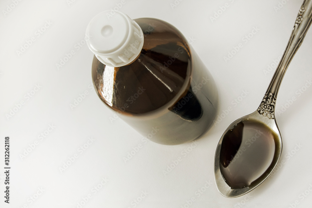 bottle and cough syrup in a spoon. Close Up of a natural cough medicine in a spoon. View from above. Concept: treatment and health. bottle and cough syrup in a spoon. Close Up of a natural cough medicine in a spoon. View from above. Concept: treatment and health.