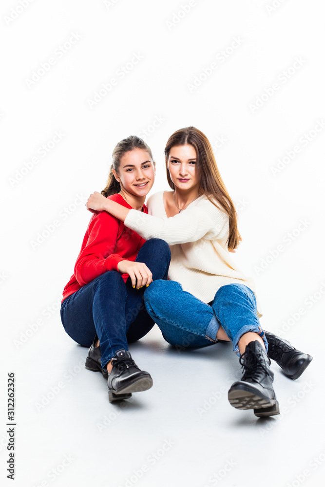 Two teen girl friends have fun sitting on the floor isolated on white background Two teen girl friends have fun sitting on the floor isolated on white background