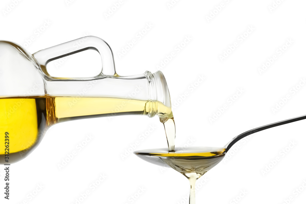 Pouring cooking oil from jug into spoon on white background
